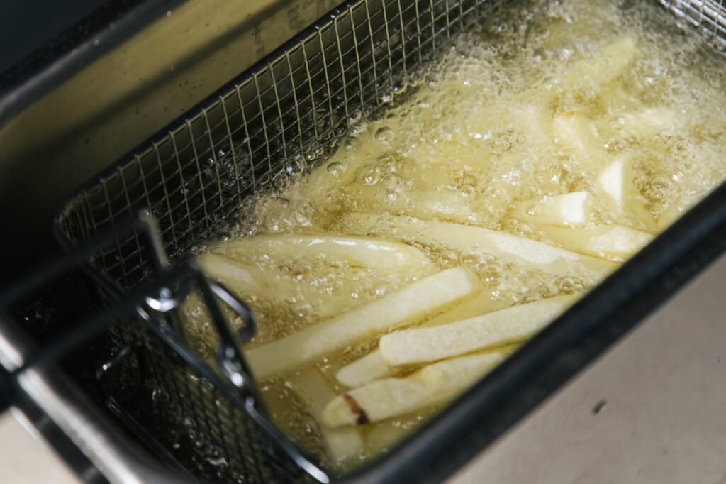 Close-up of french fries being deep-fried in a fryer, sizzling in oil.